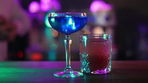 Serving two cocktails on the bar. Blue and red cocktails with ice Stock Footage 196981997