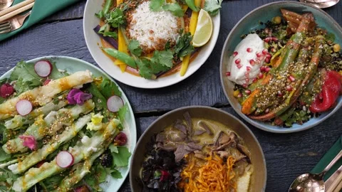 Serving two plates with healthy organic vegan meals to the black wooden table Stock Footage 139840909