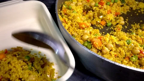 Serving vegetable couscous from a pan to a dish. Video stock 101780607