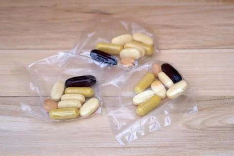 Servings of tablets of different sizes and colors in bags. Stock Photos