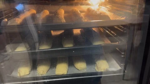 Sesame covered dough rolls baking on trays inside oven Stock Footage 317981791