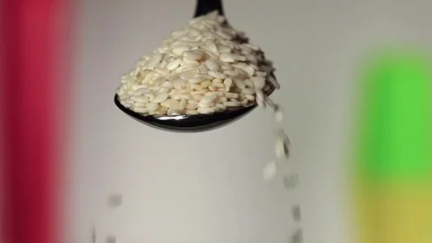 Sesame not fried falling from the iron spoon. Blurred background. Slow motion Stock Footage 75523056