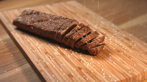 Sesame seeds falling on sliced rye bread. Media Stock Footage 321450241