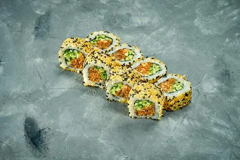 Sesame sushi roll with avocado, eel and cheese on a gray background. Noise ad Stock Photos