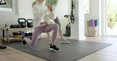 Session starting as client is stepping into lunges with trainer guiding posture Stock Footage 342927577