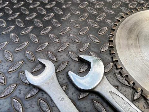 Set of 2 wrenches and circular saw blades placed on a dark steel background - Stock Photos