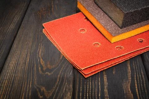 Set of abrasive tools and brown sandpaper on black vintage wooden boards Stock Photos