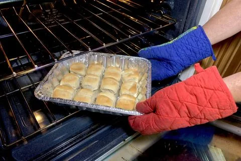 A set of baked buns being removed from an oven in preparation for dinner. Stock Photos