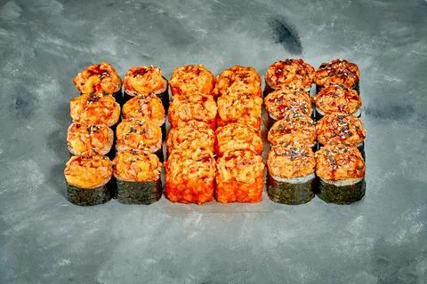 Set of baked sushi rolls with baked salmon and cheese filling on a gray backg Stock Photos