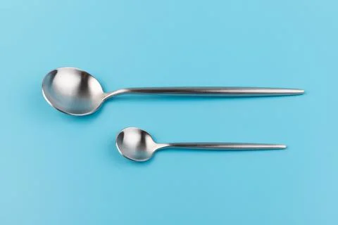 Set of a big and a small spoon on blue background, top view. Space for text Stock Photos