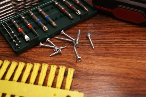 A set of bits and mounting screws on a dark wooden table. Stock Photos