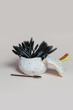 Set of black brushes for eyebrows and eyelashes in a porcelain glass Stock Photos