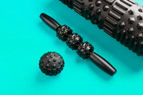 A set of black bumpy foam massage rollers, body rollers, rubber balls on a bl 스톡 사진