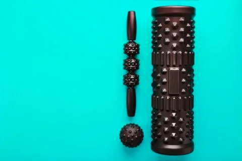 A set of black bumpy foam massage rollers, body rollers, rubber balls on a bl Stock Photos