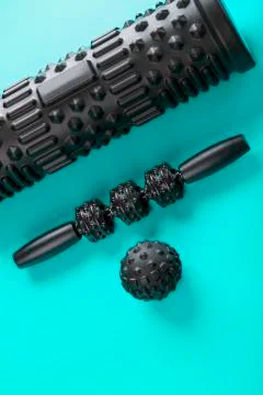 A set of black bumpy foam massage rollers, body rollers, rubber balls on a bl Stock Photos