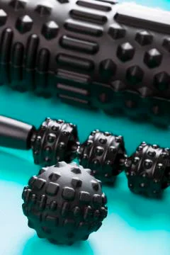 A set of black bumpy foam massage rollers, body rollers, rubber balls on a bl Stock Photos