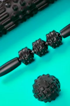 A set of black bumpy foam massage rollers, body rollers, rubber balls on a bl Stock Photos