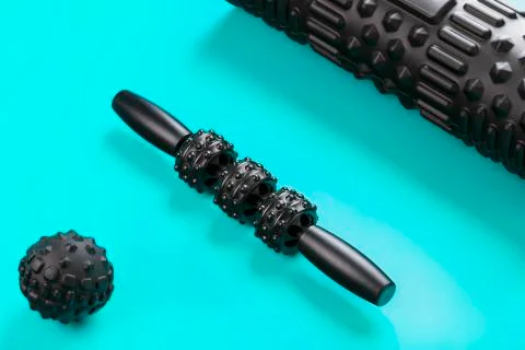 A set of black bumpy foam massage rollers, body rollers, rubber balls on a bl Stock Photos