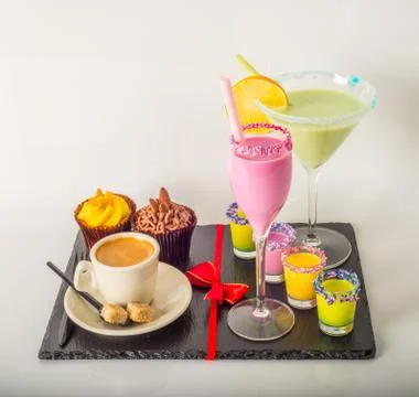 Set of black coffee in a cup, two muffins with a green and pink drink Stock Photos