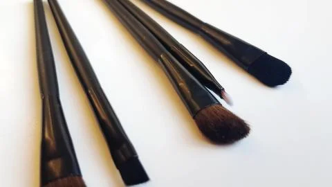 Set of black makeup brushes and cosmetics on a white background, beauty conce Stock Photos