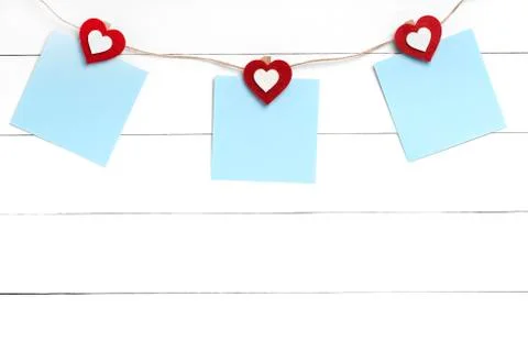 Set of blank stickers hanging on string behind white wooden surface Stock Photos