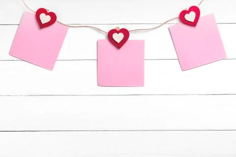 Set of blank stickers hanging on string behind white wooden surface Stock Photos