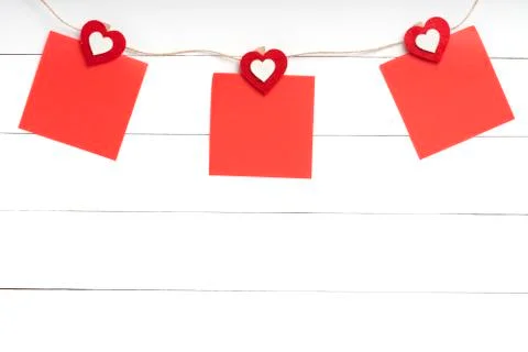 Set of blank stickers hanging on string behind white wooden surface Stock Photos