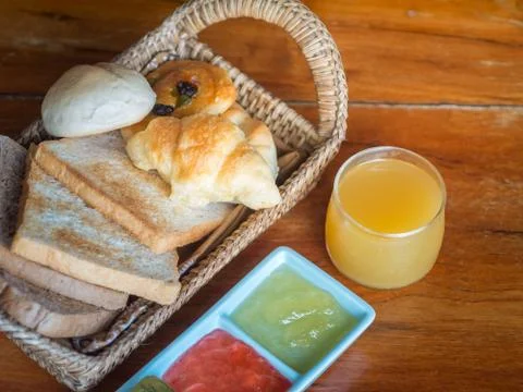 Set of bread in wicker basket with jam and orange juice Stock Photos