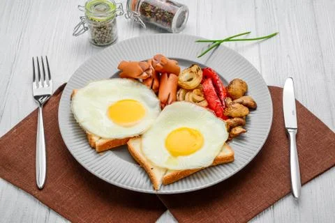 Set for breakfast fried eggs, grilled vegetables, sausages. Bread on a wooden Stock Photos