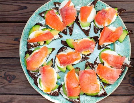 Set of bruschettas with rye bread, salmon and cream cheese on a dark wooden.. Stock Photos