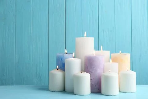 Set of burning candles on table against light blue wooden background. Space f Foto stock