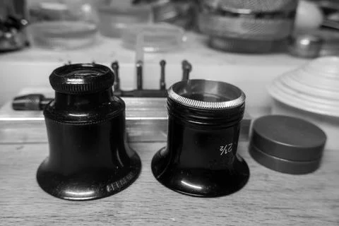 Set of camera lenses of different sizes on a wooden table in grayscale Foto stock