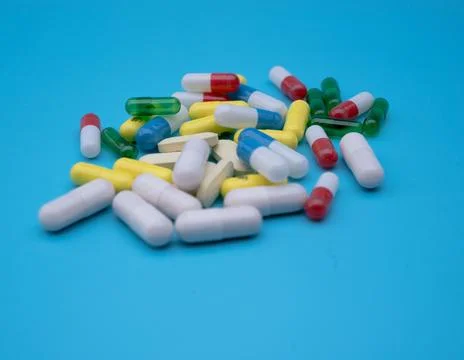 Set of capsules of different colors on a blue background. Health concept. Stock Photos