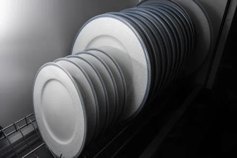 Set of clean white plates located in cupboard Stock Photos