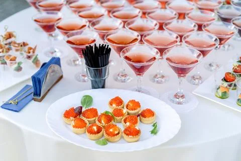 Set of cold snacks, red caviar in baskets. In the background drinks in beauti Stock Photos