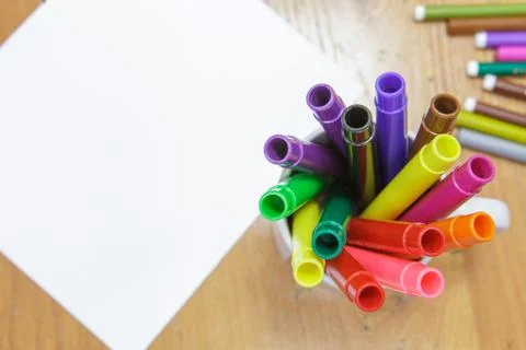 A set of colored markers and a sheet of white paper on the table. Stock Photos