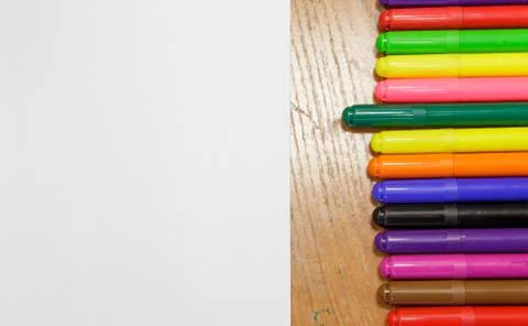 A set of colored markers and a sheet of white paper on the table. Stock Photos