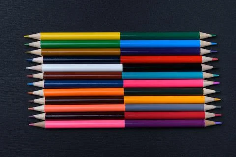 A set of colored pencils sharpened on both sides on a black chalk board Stock Photos