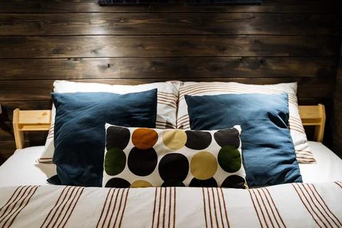 A set of colored pillows at the head of the bed. Cozy wooden room. Cozy doubl 写真素材