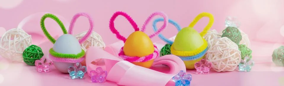 Set of colorful eggs with Easter bunny ears lie in a satin ribbon Stock Photos