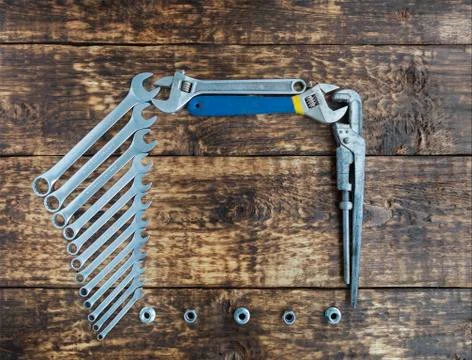Set of combination wrenches and old adjustable wrenches on an old wooden back Stock Photos