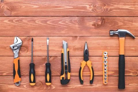 Set of construction tools on a brown wood background. Hammer, wrench, pliers Stock Photos