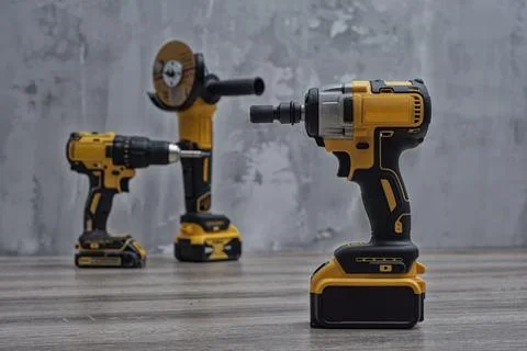 Set of cordless power tools, including a drill, impact driver, and grinder on Stock Photos