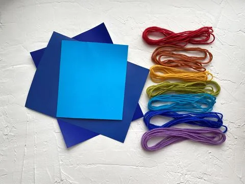 Set for creativity: blue paper and multicolored yarn. Stock Photos