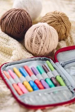 Set of crochet hooks with multi-colored handles in an organizer and balls o.. Stock Photos