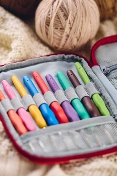 Set of crochet hooks with multi-colored handles in an organizer and balls o.. Stock Photos