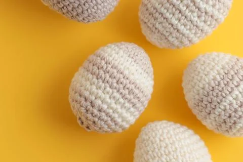 Set of cute striped pattern crocheted eggs, pastel color on a yellow Foto stock