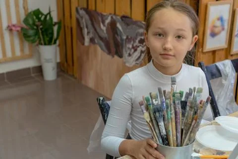 A set of different color brushes in the hands of the girl. Interior of the ar Fotos Stock