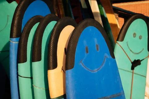 Set of different color surf soft boards with smile for beginers in a stack by Stock-Fotos