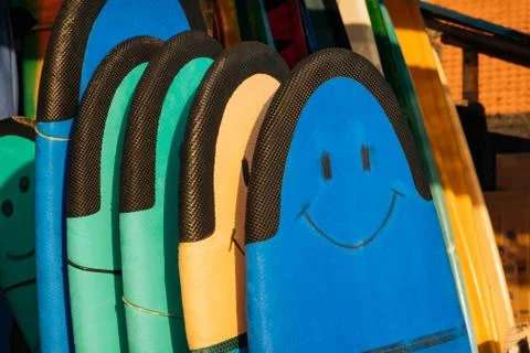 Set of different color surf soft boards with smile for beginers in a stack by Fotos de archivo